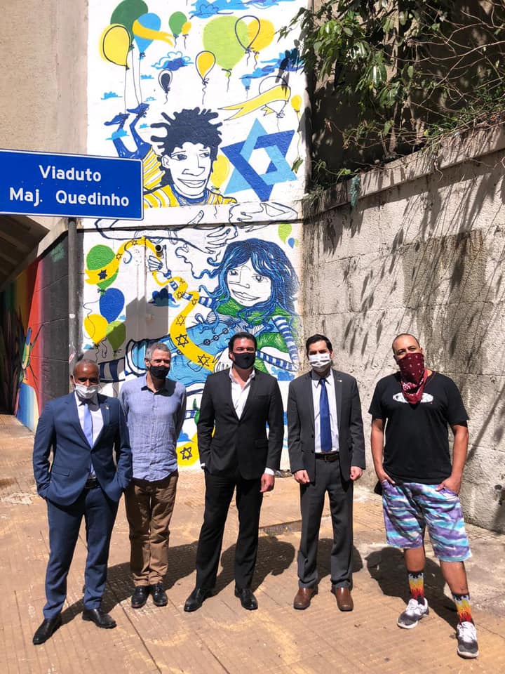 Na frente do mural encontram-se o Vice Cônsul de Israel, o Secretário Municipal de Cultura, o Secretário de Relações Internacionais, Luiz Alvaro, o Cônsul de Israel e o Artista, Luiz Birigui.